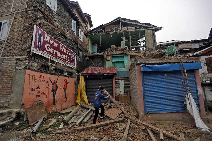 Un hombre recoge los restos de parte de su casa, que se ha derrumbado. | REUTERS