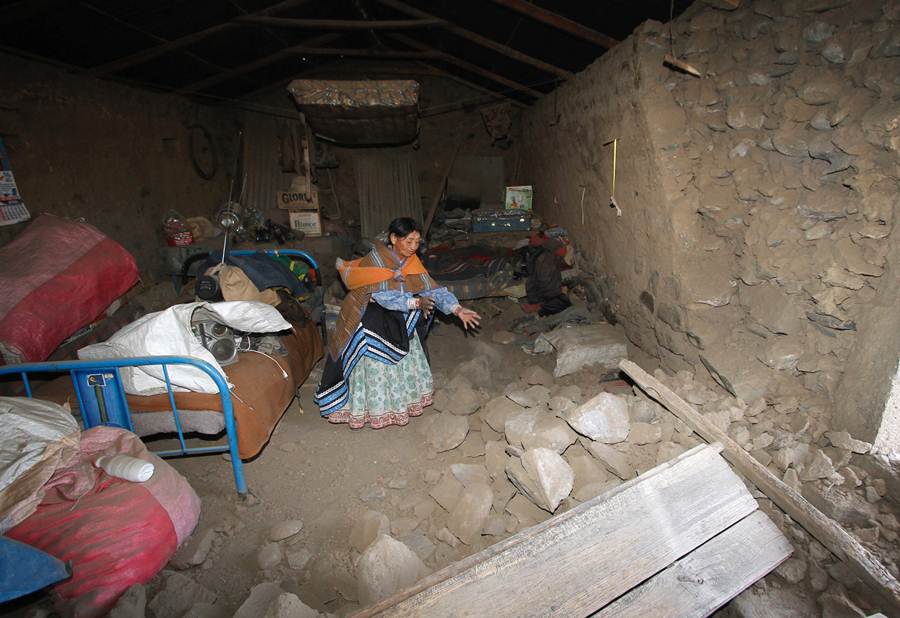 Una señora muestra el derrumbe de su casa tras el terremoto. | REUTERS