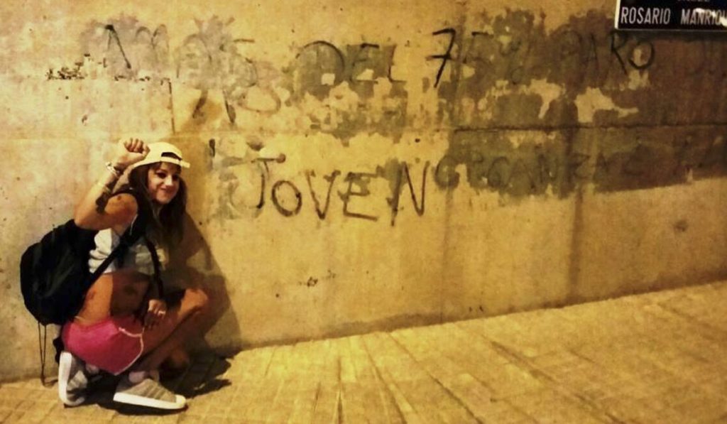 Aisha Hernández, activista de ANC, junto a la pintada que aún permanece en la pared. DA
