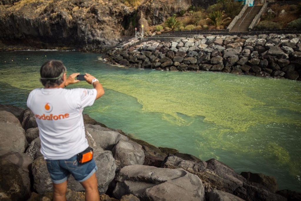 Unos bañistas, ayer, en Radazul, con las manchas de cianobacterias frente a ellos. Andrés Gutiérrez