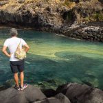 Unos bañistas, ayer, sentados en Radazul, con las manchas de cianobacterias frente a ellos. Andrés Gutiérrez