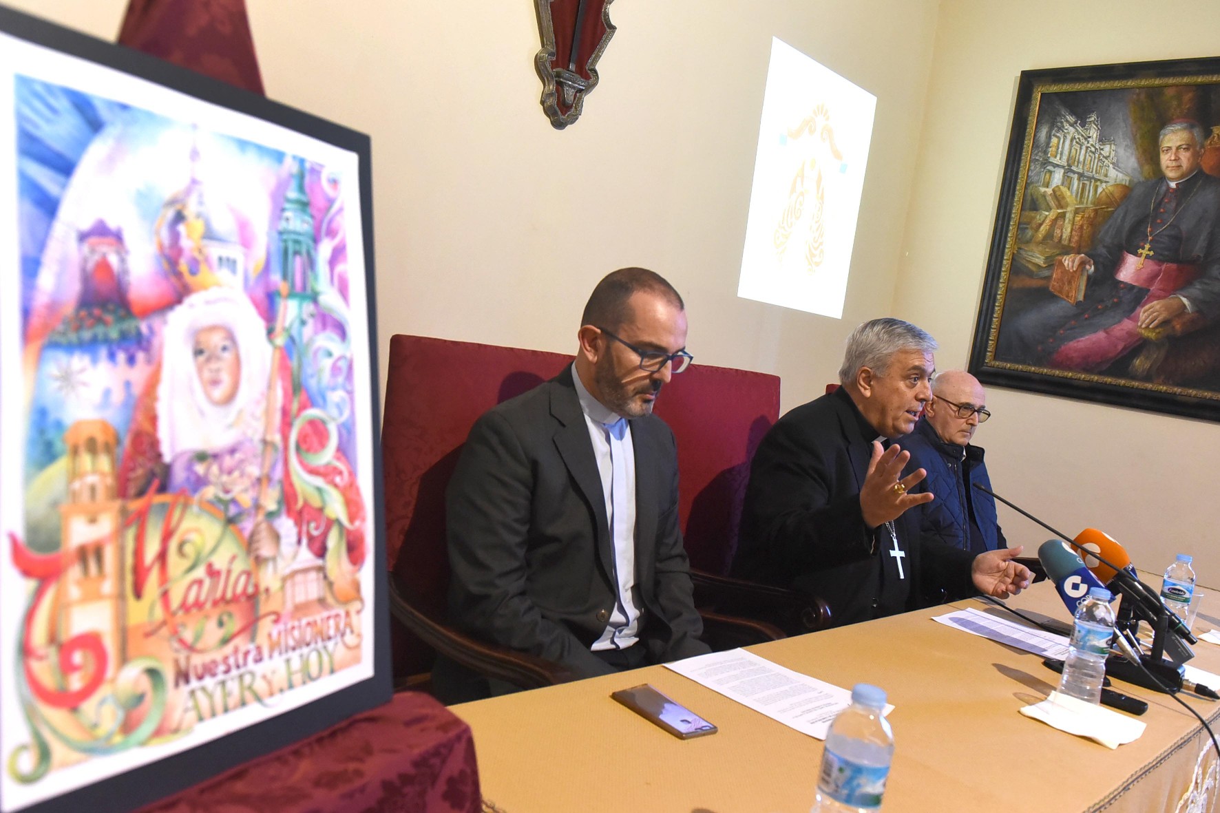 El delegado episcopal Jesús Gil Agüín, el obispo Bernardo Álvarez y el rector Daniel López, ayer, en rueda de prensa junto al cartel de la visita. Sergio Méndez