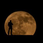 Excursionista sobre un montículo en el Parque Nacional del Teide con la Luna al fondo / Foto: Edson Vandeira