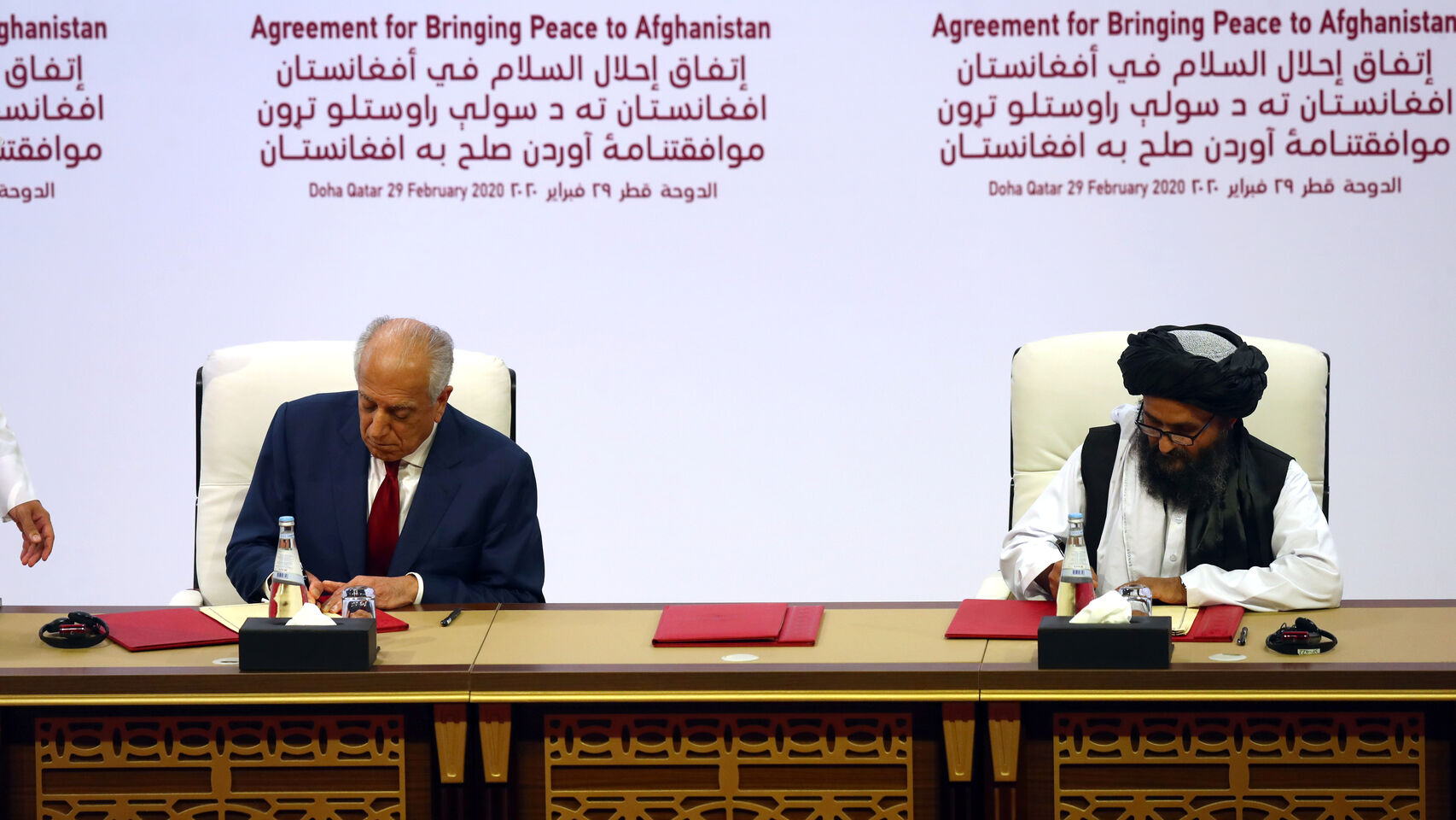 El líder talibán, Mullah Abdul Ghani Baradar, y el representante especial para la paz de EEUU, Zalmay Khalilzad, firmando el acuerdo. Reuters