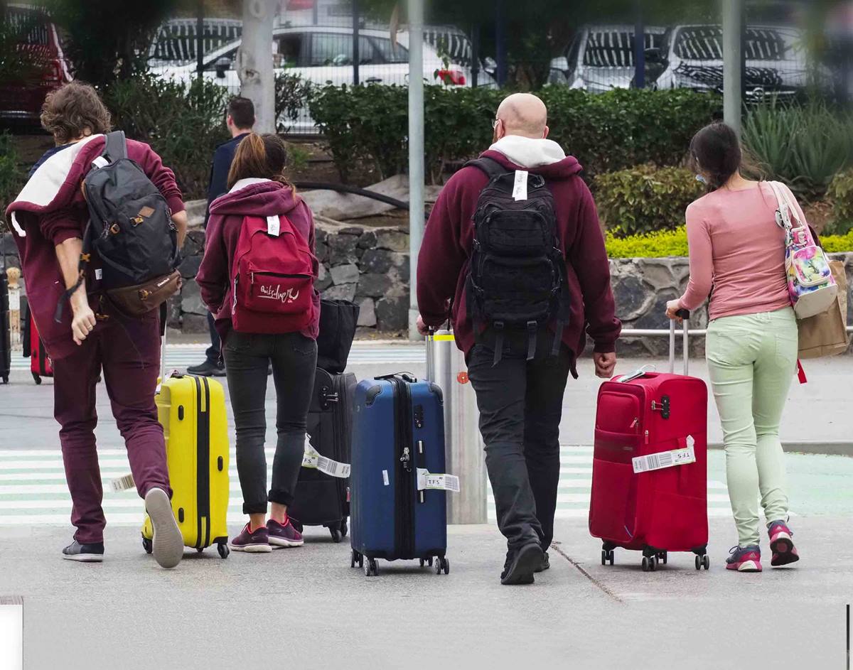 Varios turistas alemanes se dirigen a una de las guaguas estacionadas por fuera de la terminal tras aterrizar ayer en el aeropuerto Tenerife Sur. Sergio Méndez