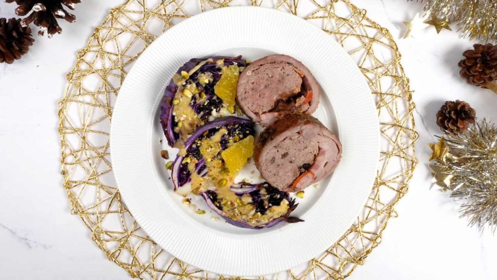 Un plato de redondo de Navidad con lombarda asada sobre una mesa decorada de Navidad