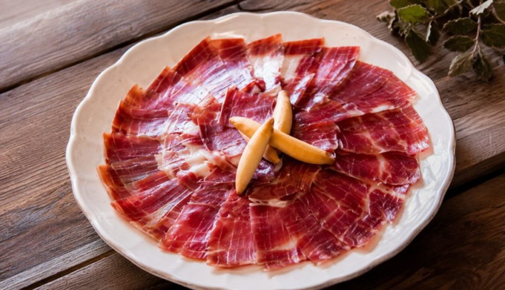 Un plato de jamón ibérico perfectamente cortado sobre una mesa. | DA